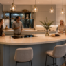 Isla de cocina curva con placa integrada, gabinetes azul grisáceo y personas conviviendo